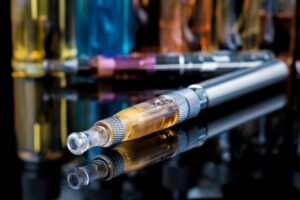 Electronic cigarette with colourful glass e-juice bottles in background
